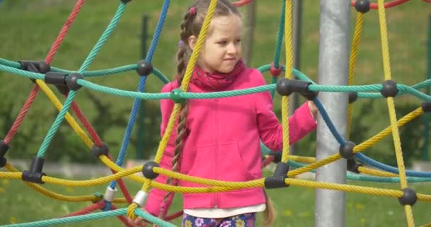Uma criança em uma gaiola de cordas pequenas . — Vídeo de Stock