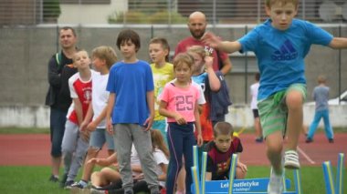 Küçük bir çocuk engellerin üzerinden çalışması sırasında atlar.