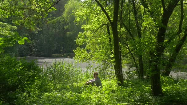 Pihenés a sikátorban turisztikai guggolva a Park kattint a telefon gyaloglás révén magas fű zöld fák frissesség a napsütéses nyári nap napfény hétvégén — Stock videók