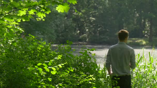 Toerist die zich onder de groene weelderige struiken rusten in Park rondkijken geïnspireerd toeristische groene bomen versheid zonlicht Man besteedt weekend in het voorjaar — Stockvideo