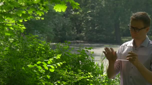 Homme clique tablette virtuelle sous Maple Tree Walks Away Homme d'affaires dans le parc Forex Trading Paiement Commande en ligne Sur Internet Touriste à Park Springtime 