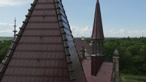 Dachy i wieże Moszna Castle Park trawników zielonych drzew w słoneczny dzień horyzont niebieski niebo eklektyczny stylu Pałac neogotycki neorenesansowy style skrzydeł — Wideo stockowe