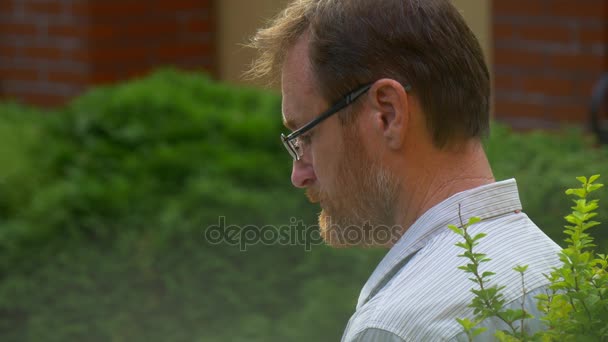 Mann mit Brille liest im Freien ein Buch — Stockvideo