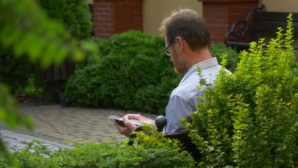 Man Resting in a Park. a Man Holding a Book — Stock Video