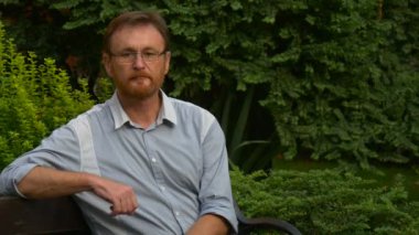 Park düşüncesinde oturan gözlüklü adam