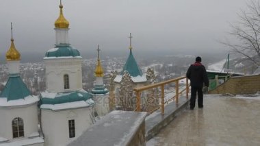 Aziz Nicholas Kilisesi Kutsal dağlar Lavra Parkı içinde kış köknar ağaçları manzara bulutlu karlı gün Ortodoks katedrali mağara manastır için aşağıda yürüyen adam
