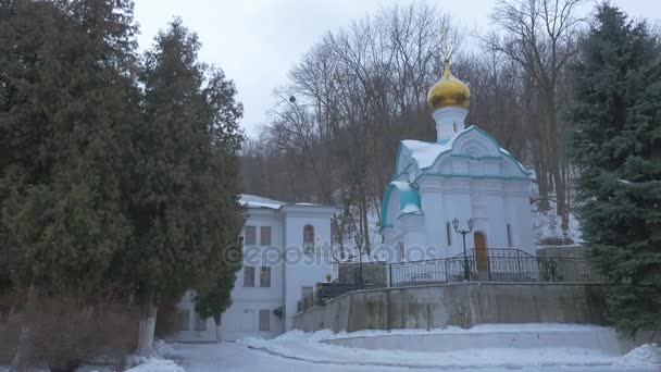 Parken runt kapellet i St. Nicholas kyrkan heliga berg Lavra grotta kloster i vinter Fir träd landskap grumligt snöig dag religiösa byggnader — Stockvideo