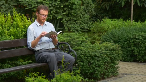Elderly Man Glasses Reading Book Park Bench Put Book Aside — Wideo stockowe
