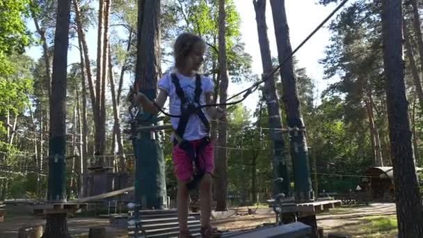 Kleines Mädchen fährt über eine Seilbrücke — Stockvideo
