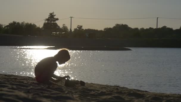 Chica está en una pequeña playa de arena cerca de un río — Vídeo de stock