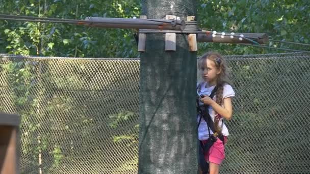 Meisje neemt uit een Carbiner zet het aan andere kabel gelukkig meisje is in touw avonturenpark in zomer zonnige dag kind heeft plezier bezet door Sport klimmen door bomen — Stockvideo