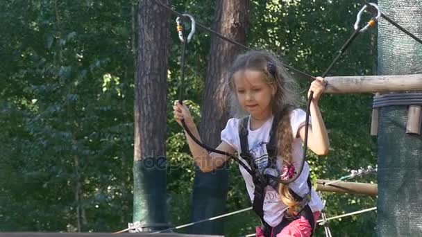 Flicka Kid når en mitt av en rep Road äventyr Rope Park glad tjej vilar i sommar solig dag barn har roligt upptas av idrott på Ukrainas natur — Stockvideo