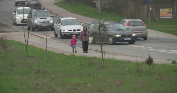 Dag van de bemande ruimtevaart Opole Cityscape auto's zijn gedreven grootmoeder en Kid bewolkt Lente wandeling langs het gebrul groen gazon Juvenile bomen — Stockvideo