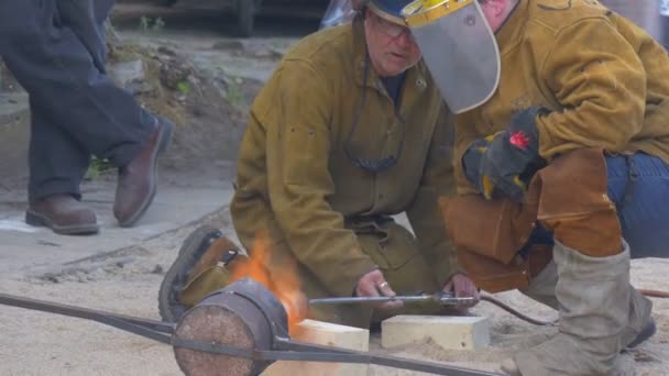 Festival van de hoge temperaturen in Wroclaw stad Polen werknemers zijn Molding een hardmetaal in een emmer met een vuur verbrand mannen praten proberen te maken het smelten — Stockvideo