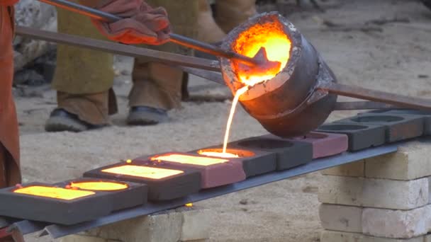 Män i säkerhet kläder hälla Orange smält metall i formarna av tur höga temperaturer festivalen Outoors på en gatan arbetstagare som gör showen för turister — Stockvideo