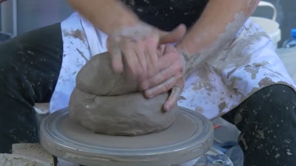 Potter está arreglando un pedazo de arcilla en una rueda moldeando un jarrón en una rueda de cerámica haciendo una olla manos sucias al aire libre Festival de altas temperaturas en Wroclaw — Vídeo de stock