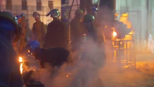 Dělníci mezi pánví s Liquid Metal kouřit zvedá siluety noční Cityscape Festival z vysokých teplot v Wroclaw lidí sleduje — Stock video