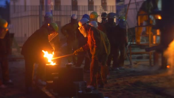 Trabajadores derramando un metal y chispas vuelan siluetas en el espectáculo nocturno de paisajes urbanos en el Festival de altas temperaturas en Wroclaw Personas con ropa protectora — Vídeos de Stock