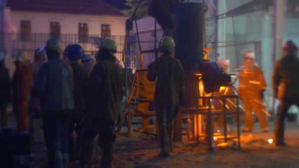 在安全服装的 wroclaw 人们的高温节上, 炉上火花附近的工人剪影照亮了地方夜间城市景观展示 — 图库视频影像
