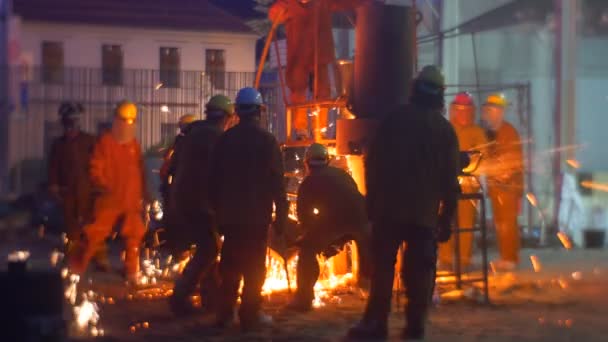 Hombres sosteniendo una cuchara que metal líquido vertiendo en siluetas cerca del espectáculo de paisaje urbano nocturno del horno en el Festival de altas temperaturas en Wroclaw — Vídeos de Stock