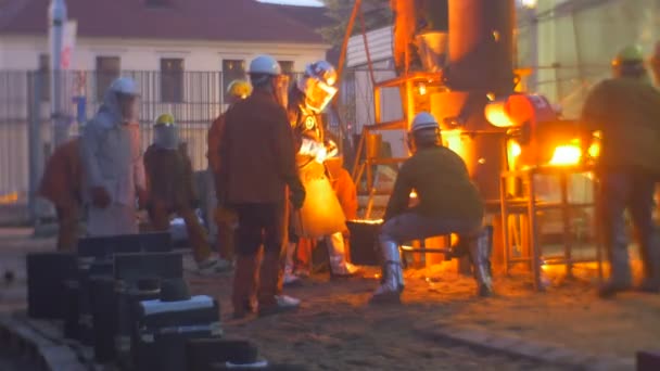 Trabajadores de fundición de metal fundido vierten en cucharón cuidadosa y rápidamente Festival de altas temperaturas en la ciudad de Wroclaw Polonia La gente está en ropa de seguridad — Vídeos de Stock