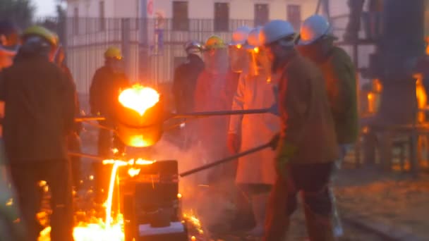 工人在黄昏时将液态金属一起浇注, 在熔炉铸造户外高温节附近铸造金属剪影 — 图库视频影像