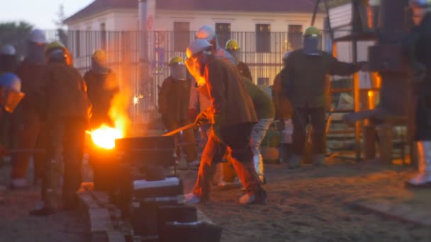 Pracowników, Casting ciepłą ciecz metalu razem o zmierzchu odlew sylwetki pomarańczowy żelaza w pobliżu pieca odlewniczego na zewnątrz Festiwal wysokich temperatur we Wrocławiu — Wideo stockowe