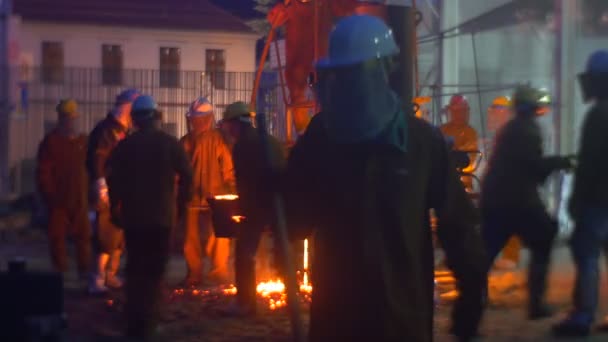 Фестиваль високих температурах у Вроцлаві працівників силуети біля печі ніч міський пейзаж рідкого металу світиться і яскраво світить людей в екранах безпеки — стокове відео