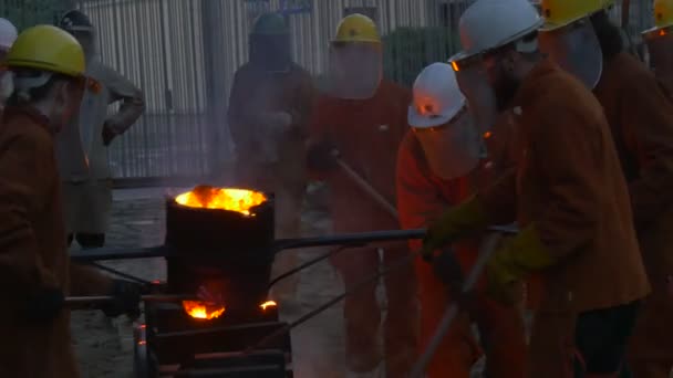 Festival des températures élevées à Wroclaw Pologne Les travailleurs dans les écrans de protection jettent du métal dans les moules prudemment Les gens sont dans des vêtements de sécurité Casques — Video