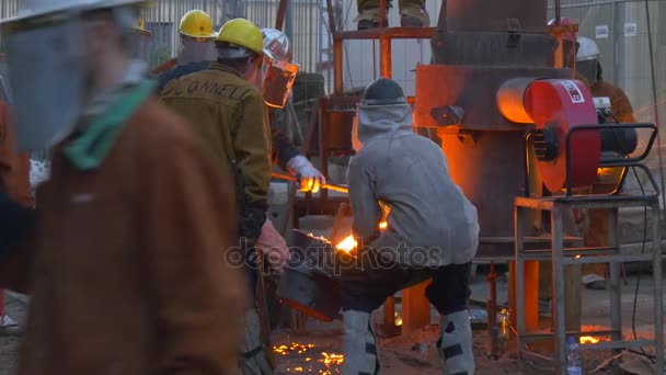 Festival de altas temperaturas en Wroclaw El hombre golpea en el horno con Crowbar Flujos de Hierro Líquido Trabajadores Artesanos Extranjeros Están Fundiendo Hierro en la Plaza de la Ciudad — Vídeos de Stock