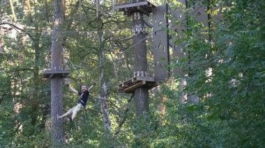 Kemer turizm çığlıklar Macera Parkı genç adam eğlenceli Ukrayna orman turizm yaz güneşli bir günde vardır heyecan ile ip yol Fiexd tarafından aşağı adam slaytlar