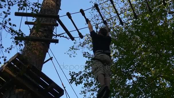 Toerist is Moving touw weg op handen Adventure Park Young Man heeft plezier in de zomer dag verplaatsen door houten logboeken hangen touwen Forest toerisme in Oekraïne — Stockvideo