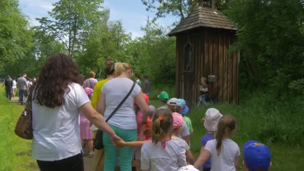 Groep kinderen gaat naar een houten kapel — Stockvideo