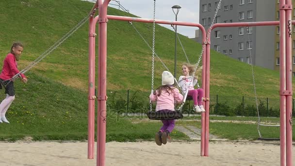 Giorno di maggio in Opole Bambine su altalene Parco giochi papà uomo adulto è oscillare insieme con i bambini parco giochi famiglie trascorre i loro fine settimana insieme — Video Stock
