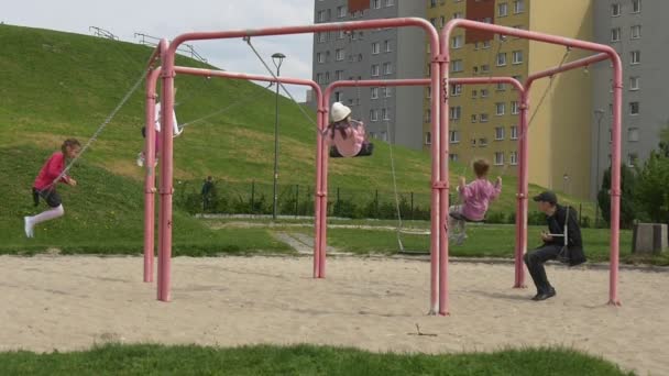 Primo maggio a Opole Polonia Le bambine oscillano sulle altalene Papà L'uomo adulto oscilla insieme ai bambini Parco giochi Le famiglie trascorrono i loro fine settimana — Video Stock