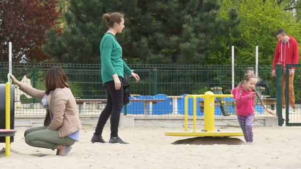 Maio dia em Opole Kid fica fora do balanço rotativo em Playground corre e cai para baixo mãe está vindo para ajudar criança está sorrindo famílias passa fins de semana juntos — Vídeo de Stock