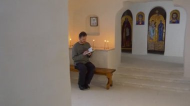 Noel Svyatogorsk Ukrayna Man yaldızlı duvar mumlar görüntülerde simgeleri yanıyor mağara Kilisesi bir bankta oturmuş İncil okur