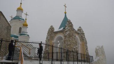 Kış günü kutsal dağ Lavra turu kış manzara bulutlu karlı gün turist Ortodoks dini binalar manastırda mağara Chapel yakınındaki iki adam