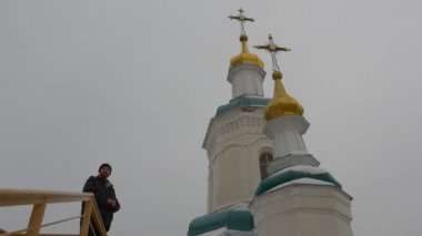 Adam kış manzara bulutlu karlı gün Ortodoks dini binalar içinde kutsal dağlar Lavra mağara manastır bir gözlem güverte gri gökyüzü yüksek kilise üstte