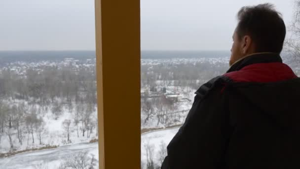 Člověk podívá na zimní krajinu, stojící na balkóně klášter na kopci svaté hory jeskyně klášter v zimě oblačno sněžení Tour Svyatogorsk — Stock video