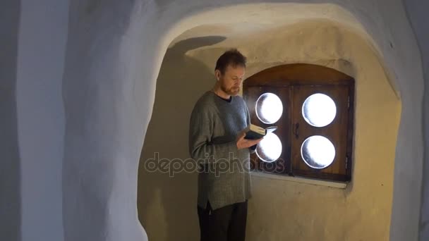 Man Inside a Small Room Cave Monastery Reading Bible Svyatogorsk Lavra Worshiper in Chapel Inside the Chalk Cave Tour to Svyatogorsk Turismo na Ucrânia — Vídeo de Stock