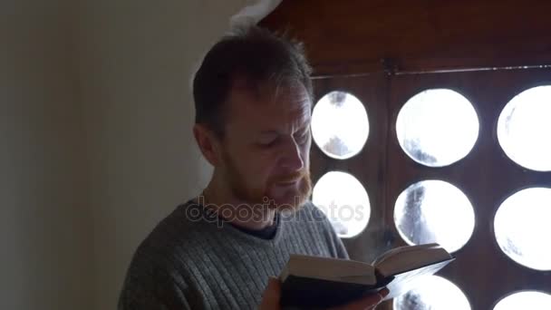 O crente reza perto da janela do portão Turista na igreja Capela dentro da caverna de giz Homem com barba está lendo Tour para Svyatogorsk Turismo na Ucrânia — Vídeo de Stock