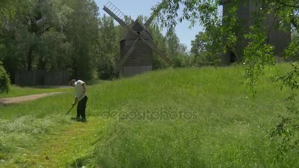 Journée des enfants Opole Man Mows the Grass Windmills Vieux bâtiments en bois Chalets dans le parc de la vieille architecture polonaise Musée ethnographique Journée ensoleillée d'été — Video