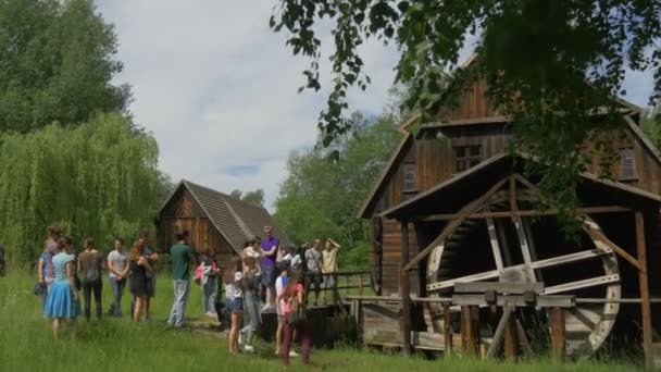 Children's Day in Opole gezinnen in de excursie Park van oude Poolse architectuur Museum Outdoors Kids leraren ouders kijken naar oude houten watermolen — Stockvideo