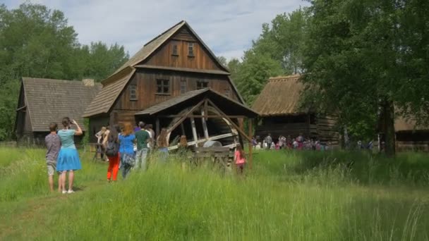 Children's Day in Opole studenten zijn nemen foto's van oude houten watermolen plattelandslandschap houten huisjes in het Park van de oude Pools Architektuur Museum — Stockvideo