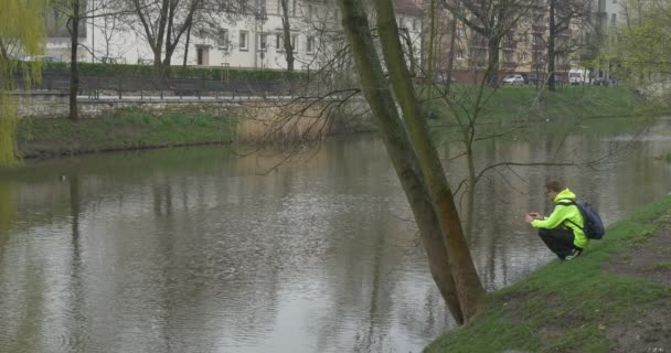 Člověk čeká přátel na břehu řeky malé — Stock video