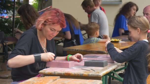 Φεστιβάλ των υψηλών θερμοκρασιών σε Βρότσλαβ γυναίκα και παιδί τεχνίτες ετοιμάζονται χύτευση καλουπιών σφράγιση με καρφιά κάνοντας μοτίβο για ένα κομμάτια του υλικού — Αρχείο Βίντεο