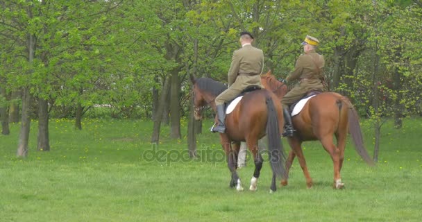 Dva vojáci v Vintage uniformě na koni koně zkouška před Parade v parku oblečení světové války druhé mužů jsou na koni zastaví lidé mezi stromy — Stock video