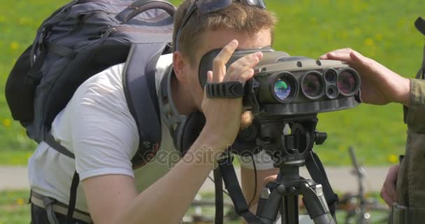 Turista está mirando a través de prismáticos Militar hombre está estableciendo el equipo de armas Exposición al aire libre Curiosas familias civiles en el evento en el día soleado — Vídeo de stock