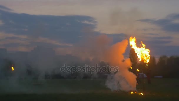 Homens silhuetas correndo ao redor da chama crepúsculo demonstrações na borda da cidade casas residenciais verde prado primavera noite pôr do sol rosa e azul céu — Vídeo de Stock